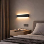 Minimalist LED Wall Light black aluminium up & down wall lamp in bedroom above bedside table.