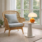 Nordic Ceramic Mushroom Table Lamp with orange base and white shade on a round table beside wicker chair in living room.