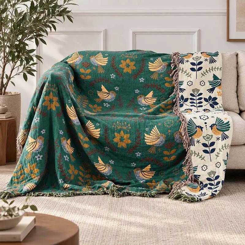 100% Cotton Reversible Throw Blanket with bird pattern; teal side on sofa, white floral reverse visible.