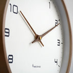 Nordic Wooden Wall Clock with white dial, black numerals and brown hands, Made by MTK, mounted on wall.