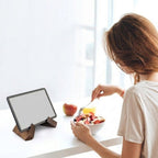 Person eating from a bowl with a tablet stand displaying a blank screen on a white surface.