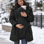 Mother wearing the black 3-in-1 maternity winter parka with baby in the babywearing panel