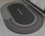 Black bath mat with 'HOME' text on a bathroom floor